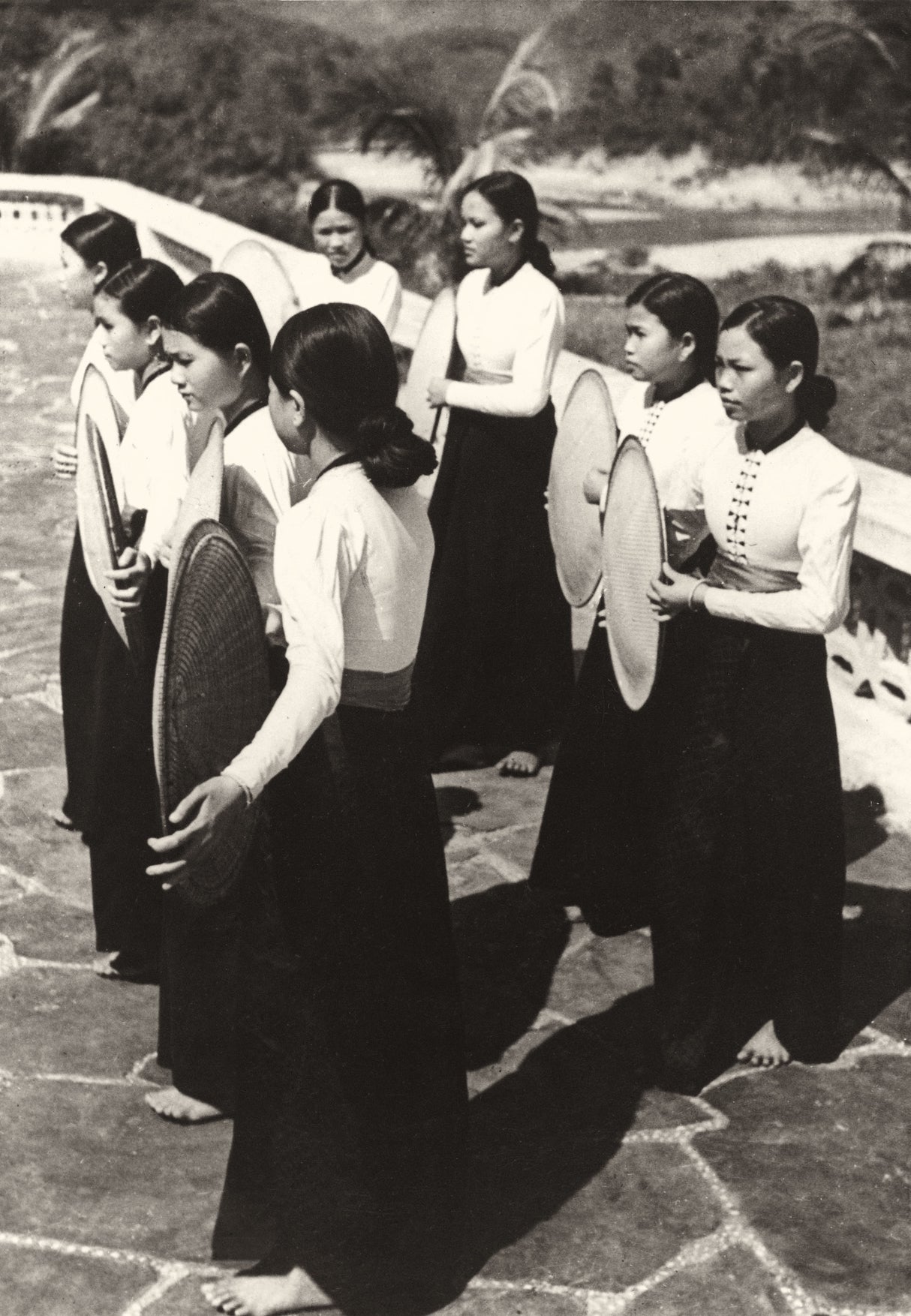 Vietnamese women in traditional dress rehearsing a fan dance outdoors in the 1950s