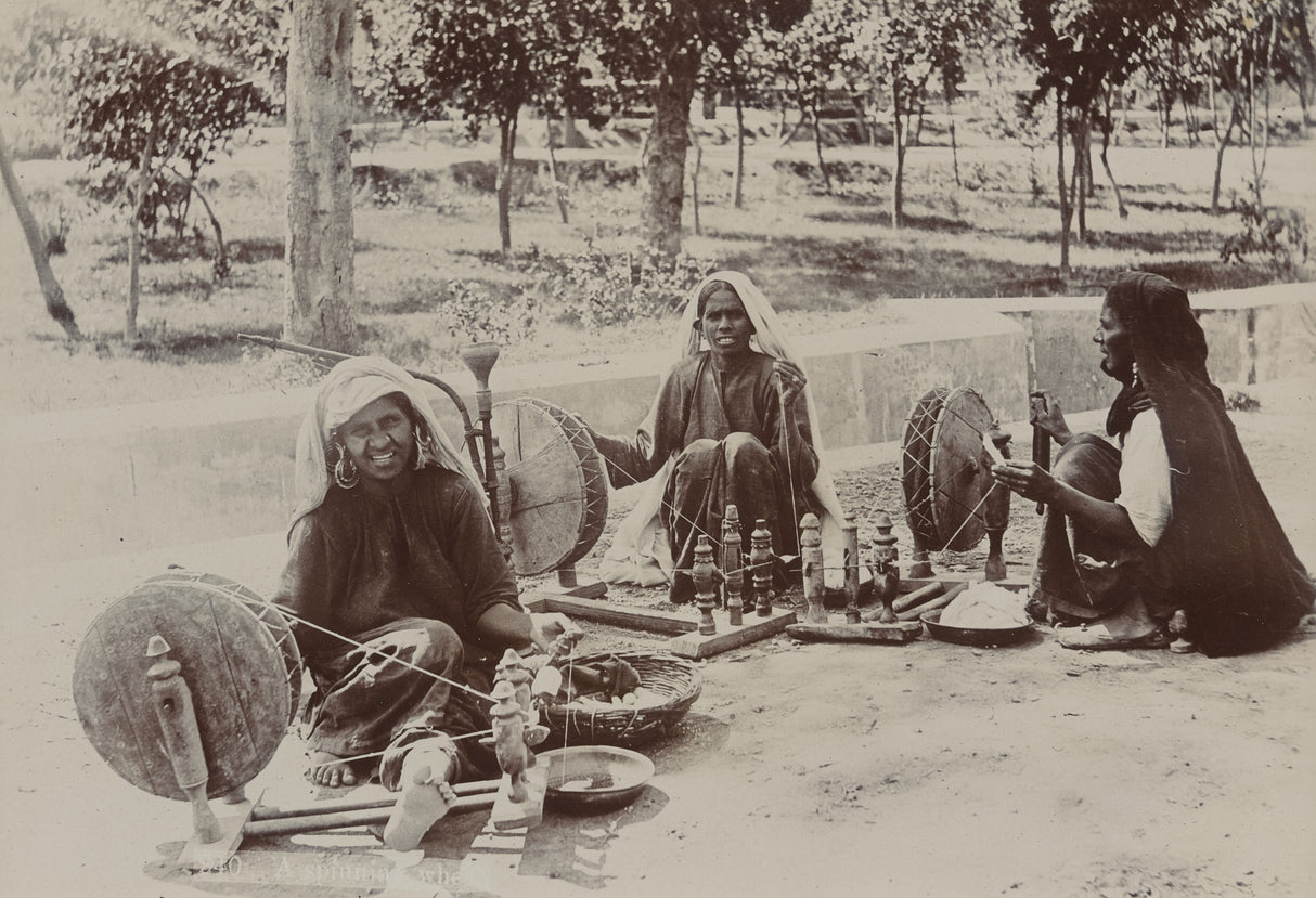 Sepia photo of Indian women using spinning wheels to prepare yarn, 1890s