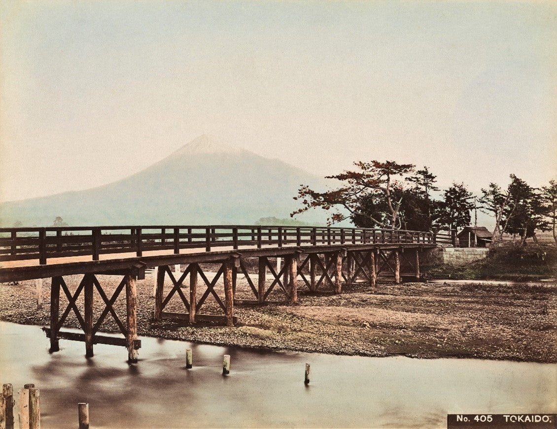 Hand-colored Meiji-era photograph of wooden bridge in Hakone with Mount Fuji in the background