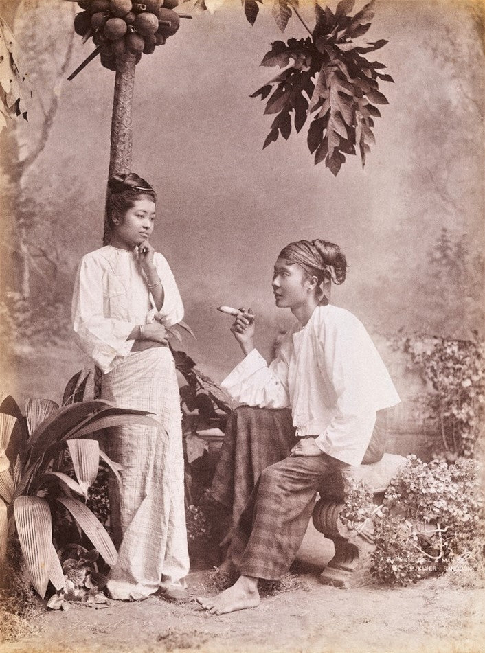 1890s studio portrait of a Burmese man seated and offering a betel nut to a standing woman, photographed by Philipp Klier.