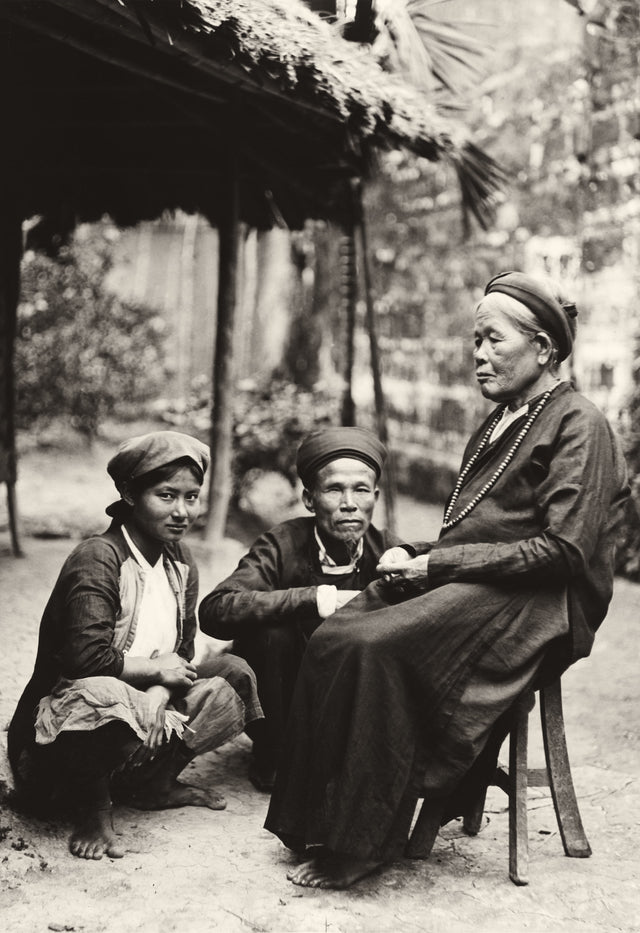 Black-and-white photo of an elder and two younger family members in a Vietnamese village, early 20th century
