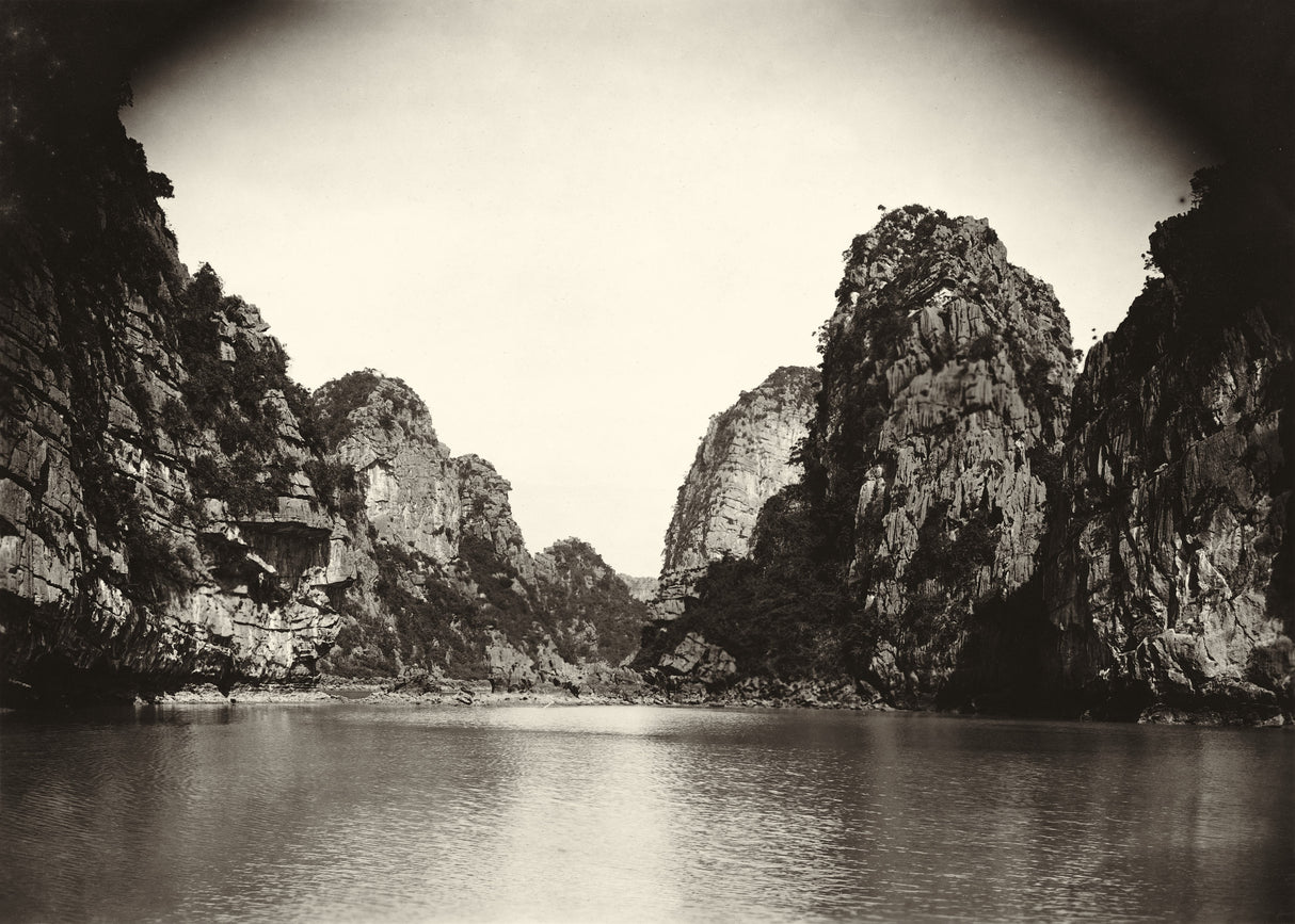 Sepia-toned view of dramatic limestone cliffs reflected in calm water in Northern Vietnam