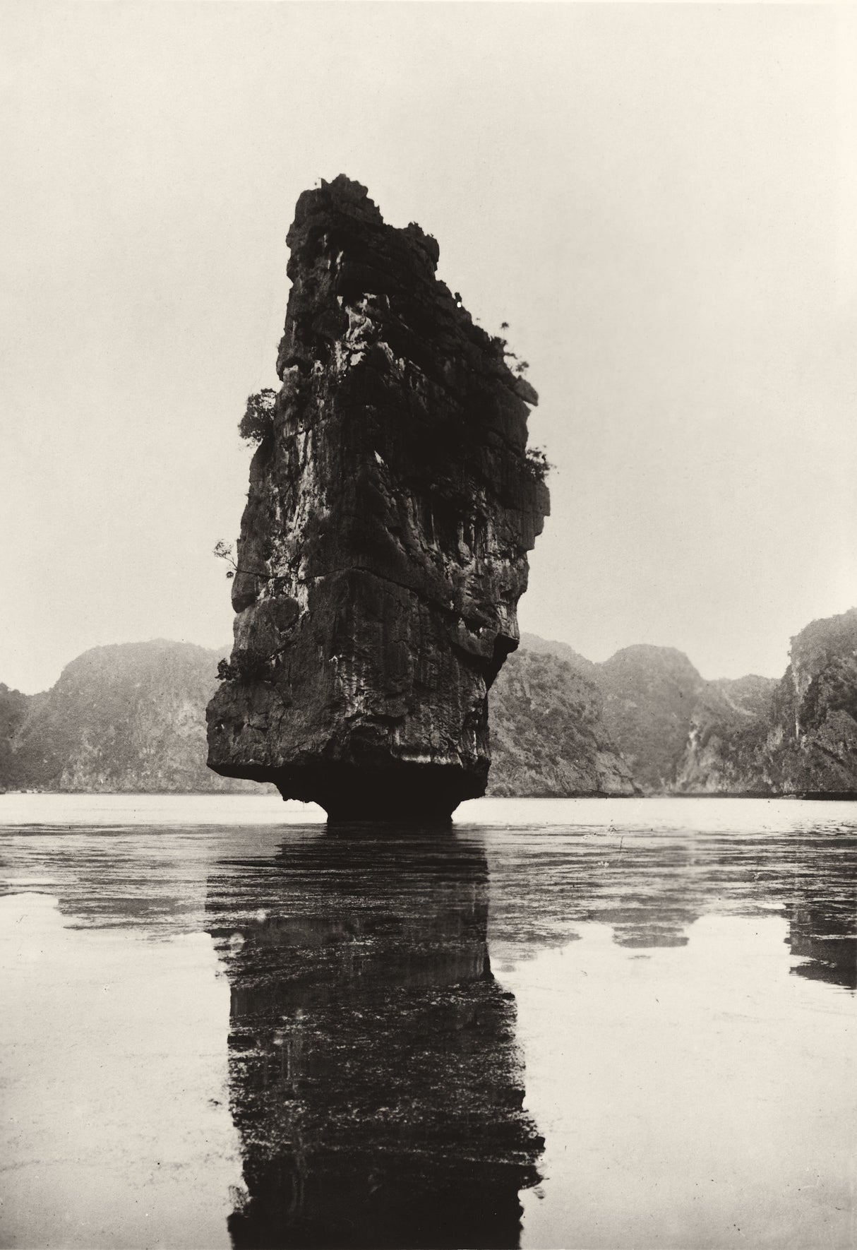 Sepia photograph of a solitary limestone formation rising from the sea in Hạ Long Bay, Vietnam