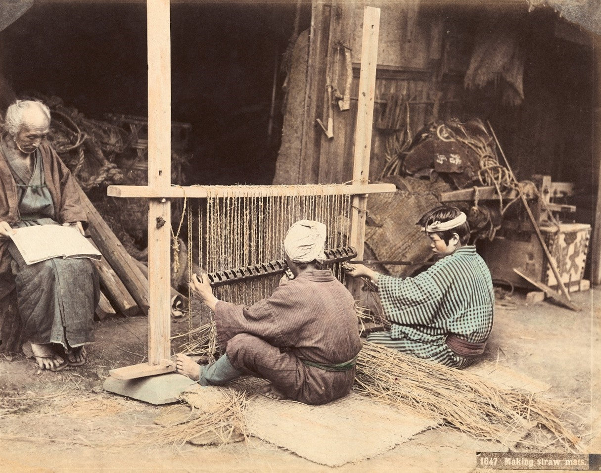 Vintage hand-colored photograph of Japanese artisans weaving straw mats using a traditional loom in the Meiji era