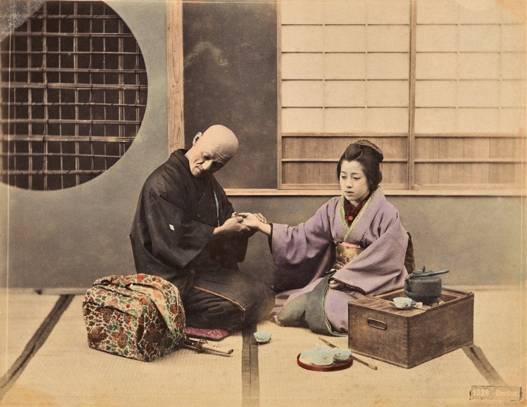 Hand-colored Meiji-era photograph of a Japanese doctor checking a patient's pulse