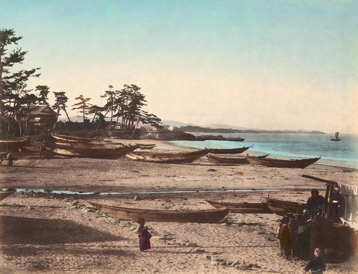 Hand-colored Meiji-era photograph of wooden fishing boats on a sandy Japanese beach