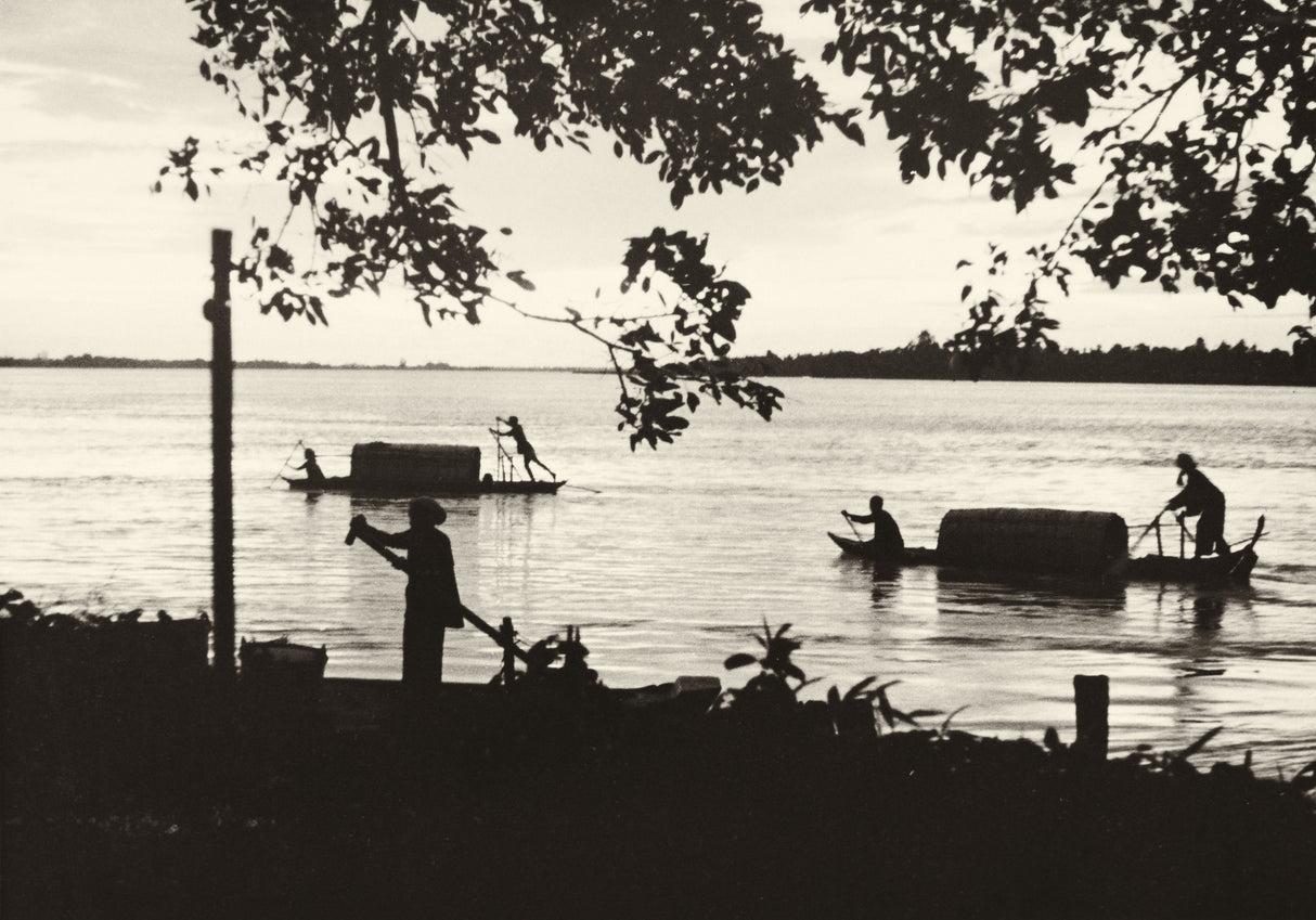 Sepia-toned photograph of bamboo rafts and boatmen on the Mekong River at dusk, circa 1920s–1930s