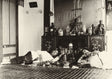 Sepia photograph of a man and woman reclining in an opium den, with ornate decor and Chinese-style furnishings