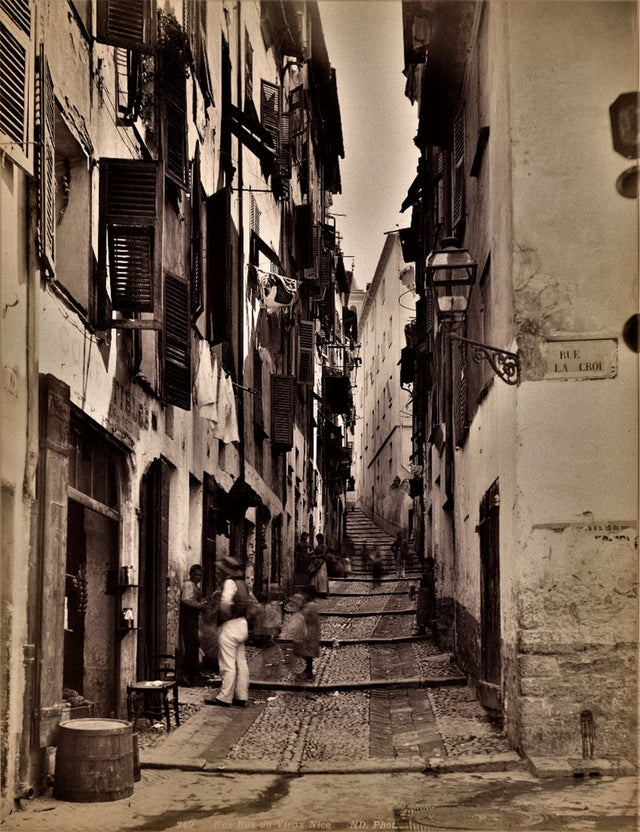 Sepia photograph of Rue de Lacroix in Vieux Nice, narrow alleyway with people and shuttered buildings