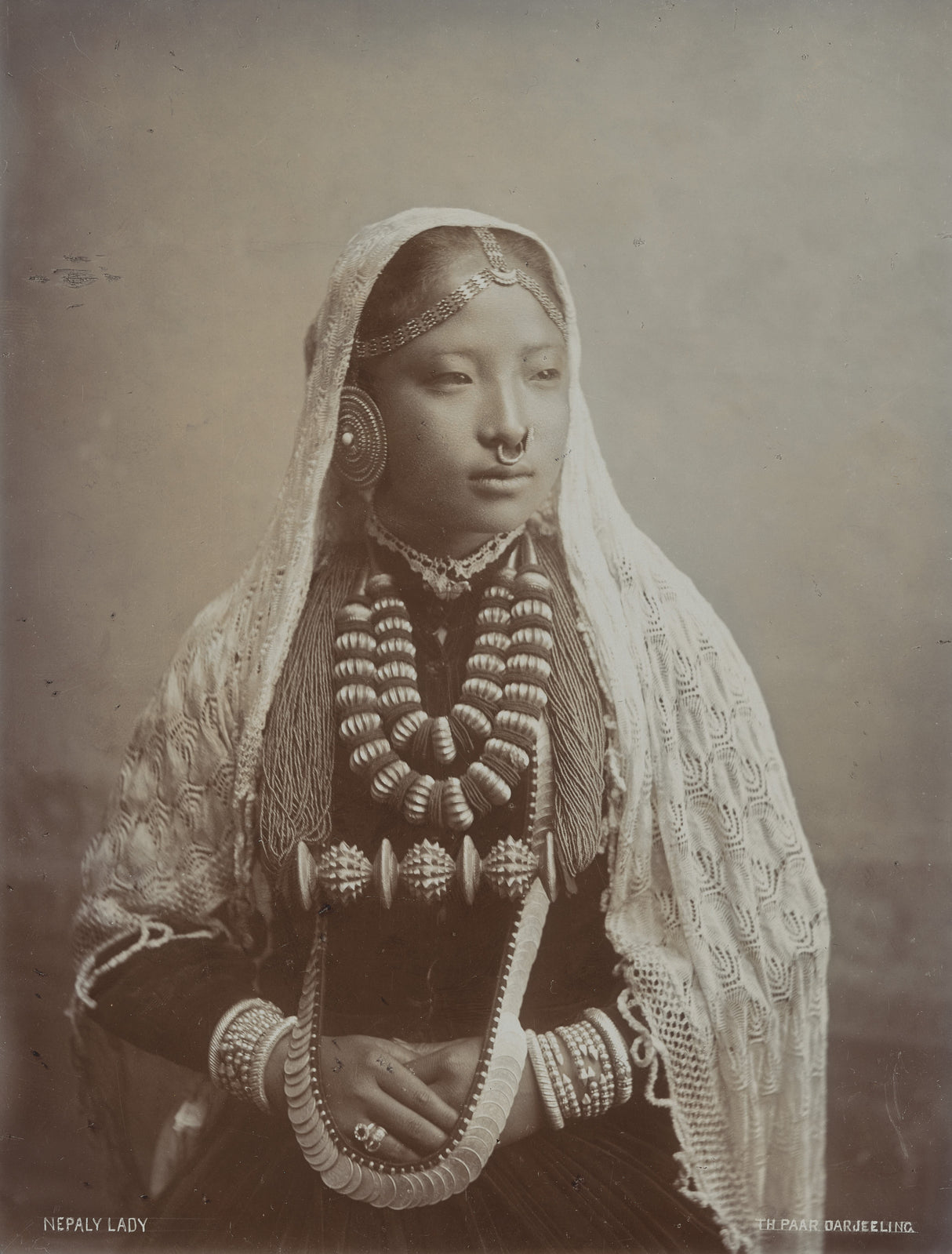 Sepia-toned 1890s studio portrait of a Nepali woman in traditional dress and jewelry, taken in Darjeeling