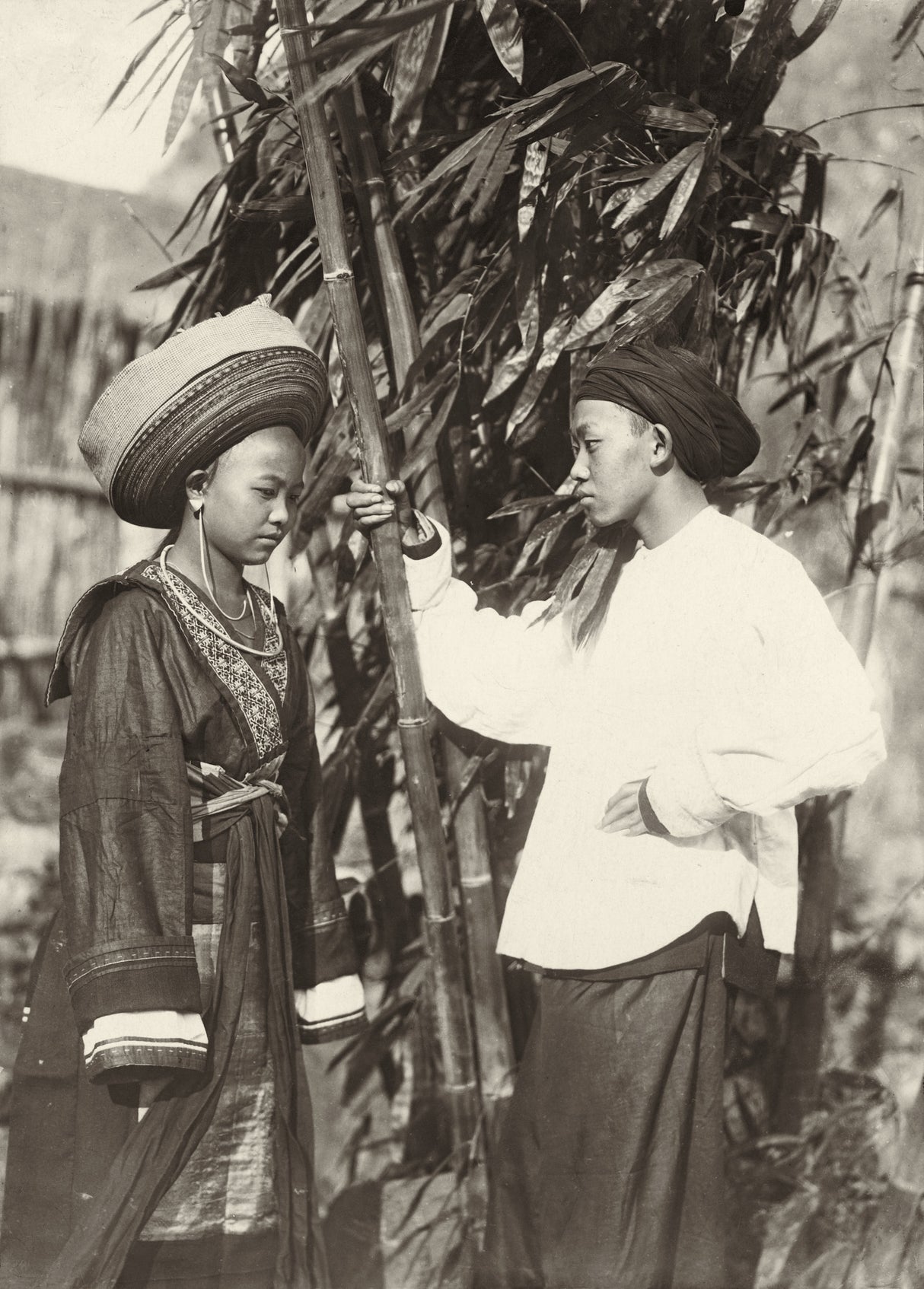 Ethnographic portrait of a young couple in traditional dress near bamboo, Yunnan–Indochina borderlands