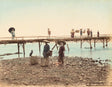 Hand-colored Meiji-era photograph of cormorant fishermen on the Tamagawa River with a wooden bridge and villagers in the background, Japan