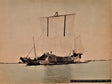 Hand-colored photograph of a traditional Japanese cargo ship with large sails, sailing on calm waters during the Meiji era.