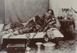Sepia photograph of an Indian courtesan reclining with hookah and traditional jewelry, 1890s

