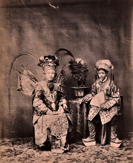 Fine art reproduction of a late Qing Dynasty photograph of two Chinese opera performers in full costume, seated and standing in a studio setting.